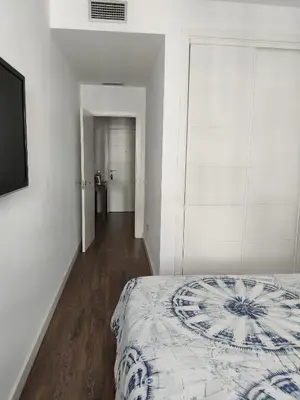 a white bedroom with a bed and a tv at Apartamento La Paraíta in Chiclana de la Frontera