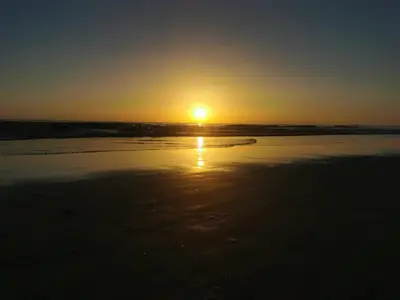 a sunset on a beach with the sun in the distance at Apartamento La Paraíta in Chiclana de la Frontera