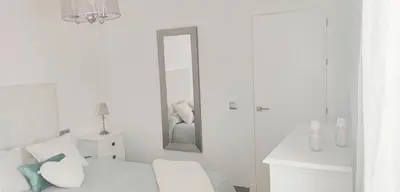 a white room with a bed and a mirror at Piso 100 metros del Centro del Pueblo 6 kilómetros de la PLAYA La BARROSa in Chiclana de la Frontera