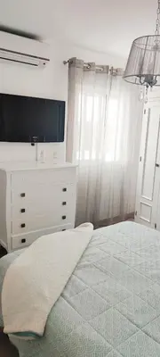 a bedroom with a bed with a tv and a dresser at Piso 100 metros del Centro del Pueblo 6 kilómetros de la PLAYA La BARROSa in Chiclana de la Frontera