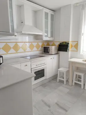 a white kitchen with white cabinets and a microwave at Apartamento Nao Victoria in Sanlúcar de Barrameda
