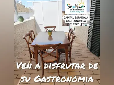 a table and chairs on a patio with a sign at Apartamento Nao Victoria in Sanlúcar de Barrameda