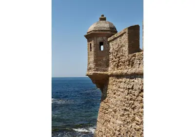a tower on the side of a wall next to the ocean at Apartamento Nebro Estrella, En el Corazón de Cádiz in Cádiz