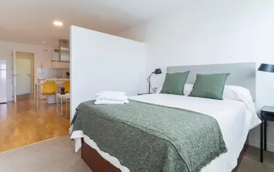 a bedroom with a large bed with a green blanket at Azvalia - Edificio Parque in El Puerto de Santa María