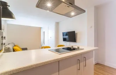 a kitchen with a counter with a sink and a tv at Azvalia - Edificio Parque in El Puerto de Santa María