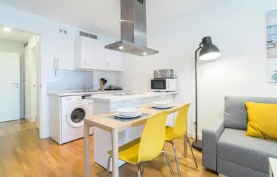 a kitchen and living room with a table and yellow chairs at Azvalia - Edificio Parque in El Puerto de Santa María