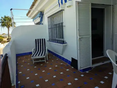 a chair sitting on the balcony of a house at Apartamento vacacional máximo 4 personas in Novo Sancti Petri