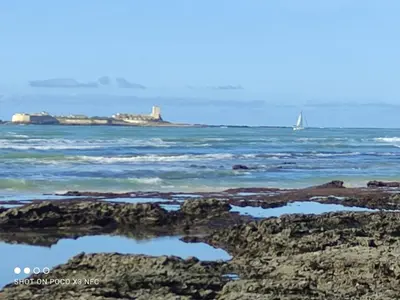 a sailboat in the ocean with a rocky beach at Apartamento vacacional máximo 4 personas in Novo Sancti Petri