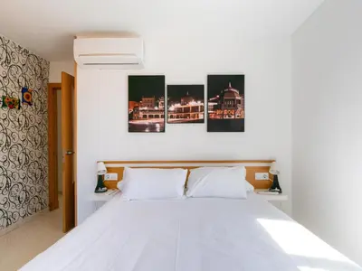 a bedroom with a white bed with four paintings on the wall at Apartamento LABORT Apartamento Boutique in Cádiz