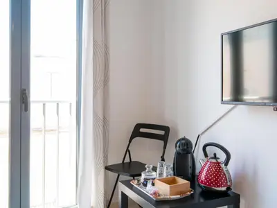 a table with a lamp and a chair next to a window at Apartamento LABORT Apartamento Boutique in Cádiz