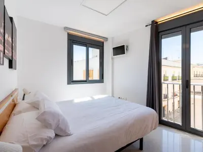 a white bedroom with a bed and a large window at Apartamento LABORT Apartamento Boutique in Cádiz