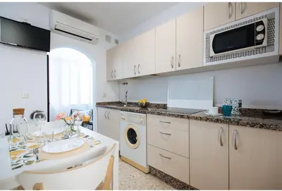a white kitchen with a sink and a microwave at LyriosHomes Chipiona Beach in Chipiona
