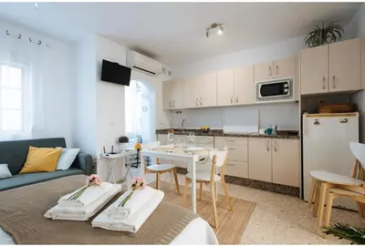 a living room with a table and a kitchen at LyriosHomes Chipiona Beach in Chipiona