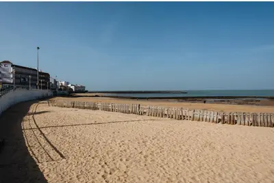 a sandy beach with a fence and the ocean at LyriosHomes Chipiona Beach in Chipiona