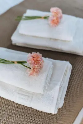 three white towels with pink flowers on a table at LyriosHomes Chipiona Beach in Chipiona