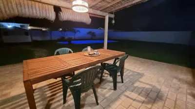 a wooden table and chairs in front of a pool at Las Casitas de la Barrosa con jardín y piscina in Chiclana de la Frontera
