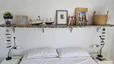 a bedroom with a bed and a shelf on the wall at Las Casitas de la Barrosa con jardín y piscina in Chiclana de la Frontera