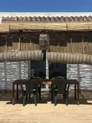a wooden table and two chairs under an umbrella at Las Casitas de la Barrosa con jardín y piscina in Chiclana de la Frontera