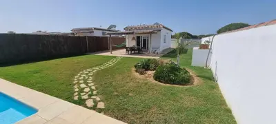 a backyard with a swimming pool and a house at Las Casitas de la Barrosa con jardín y piscina in Chiclana de la Frontera