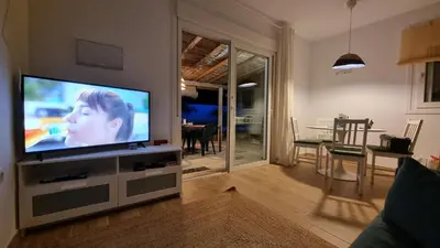 a living room with a flat screen tv on a entertainment center at Las Casitas de la Barrosa con jardín y piscina in Chiclana de la Frontera