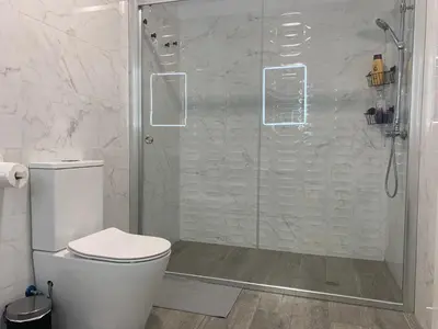 a white bathroom with a shower with a toilet at HOLIDAY ALYMA in Sanlúcar de Barrameda