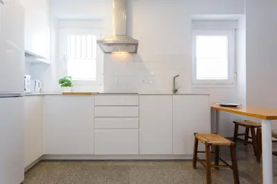 a kitchen with white cabinets and a table at Atico-Solarium CITY Hall by Cadiz4Rentals in Cádiz