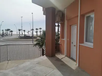 a building with a door and a street with palm trees at Apartamentos Sanlúcar Beach 2 y 3 in Sanlúcar de Barrameda
