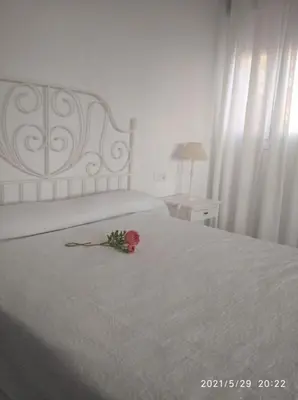 a pink rose on a white bed with a flower on it at Apartamentos Sanlúcar Beach 2 y 3 in Sanlúcar de Barrameda