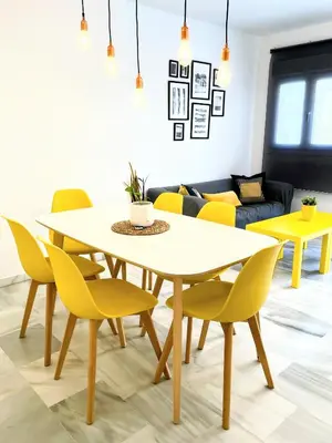 a dining room with a white table and yellow chairs at Central Apartment in Sanlucar in Sanlúcar de Barrameda
