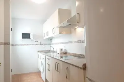 a white kitchen with a sink and a refrigerator at Central Apartment in Sanlucar in Sanlúcar de Barrameda