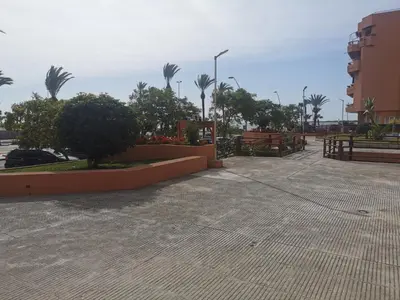a parking lot with palm trees and a building at Apartamentos Sanlúcar Beach 4 y 5 in Sanlúcar de Barrameda