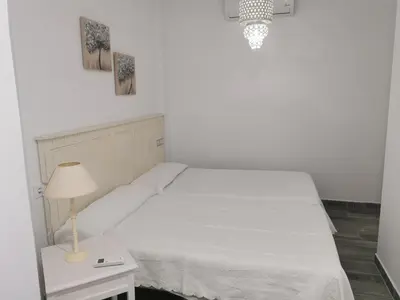 a bedroom with a white bed and a table with a lamp at Apartamentos Sanlúcar Beach 4 y 5 in Sanlúcar de Barrameda
