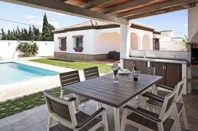 a wooden table and chairs on a patio with a pool at Vivienda Rural El chiclanero in Conil de la Frontera