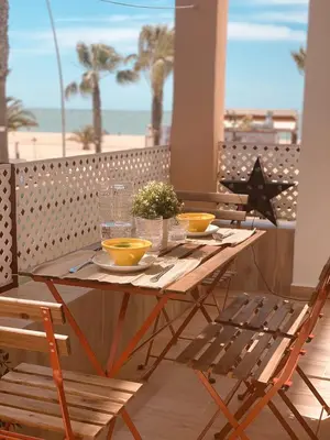 a wooden table with yellow bowls on a balcony with the beach at SibsSanlucar MARITIMO-1ª Linea de Playa in Sanlúcar de Barrameda