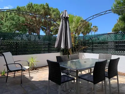 a patio with a glass table and chairs and an umbrella at Apartamento Galeón - Ole Solutions in El Puerto de Santa María