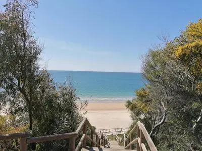 a wooden staircase leading to a beach with the ocean at Apartamento Galeón - Ole Solutions in El Puerto de Santa María
