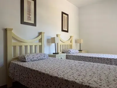 two beds in a bedroom with two lamps on the wall at Apartamento Galeón - Ole Solutions in El Puerto de Santa María