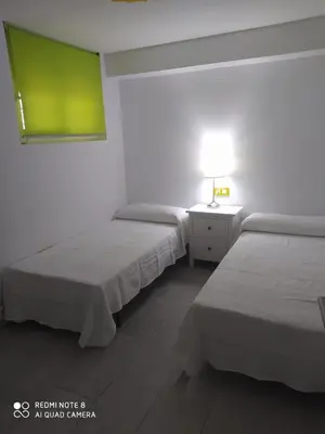 a room with two beds and a lamp on a table at Apartamento en primera línea de playa in Sanlúcar de Barrameda