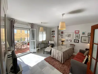 a living room with a table and a view of a patio at MAGNÍFICO ÁTICO PLENO CENTRO. Terraza 60m. Climatizado, Garaje in Sanlúcar de Barrameda