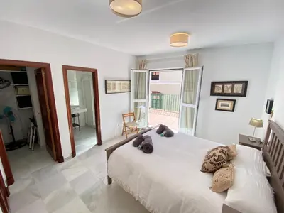 a bedroom with a large white bed and a balcony at MAGNÍFICO ÁTICO PLENO CENTRO. Terraza 60m. Climatizado, Garaje in Sanlúcar de Barrameda