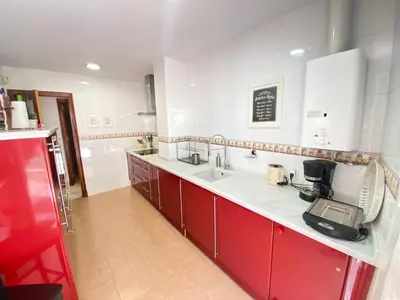 a kitchen with red cabinets and a white counter top at MAGNÍFICO ÁTICO PLENO CENTRO. Terraza 60m. Climatizado, Garaje in Sanlúcar de Barrameda
