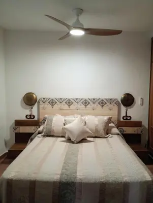 a bedroom with a large bed with a ceiling fan at Casa Jaruf CENTRO HISTÓRICO Parking Gratuito Patio petfriendly in Arcos de la Frontera