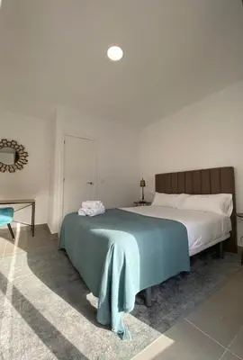 a bedroom with a bed with a blue blanket on it at Villamarta Boutique Rooms in Jerez de la Frontera