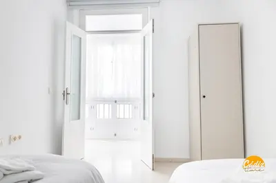 a white bedroom with a door and a mirror at Green Home by Cadiz Time in Cádiz