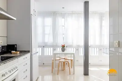 a white kitchen with a table and two chairs at Green Home by Cadiz Time in Cádiz