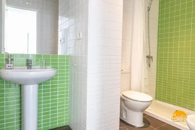 a green tiled bathroom with a toilet and a sink at Green Home by Cadiz Time in Cádiz