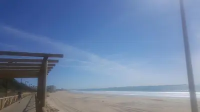 a view of a beach with a bench and the ocean at VACACIONES DE LUJO.CHALET PISCINA Y PLAYA.EL PUERTO in El Puerto de Santa María