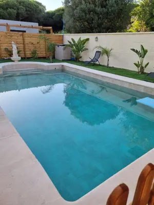 a swimming pool with blue water and two chairs at VACACIONES DE LUJO.CHALET PISCINA Y PLAYA.EL PUERTO in El Puerto de Santa María