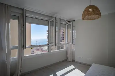 a room with large windows with a view of the ocean at Playa Victoria Ha Apartment in Cádiz