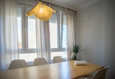 a dining room table with white chairs and a light fixture at Playa Victoria Ha Apartment in Cádiz